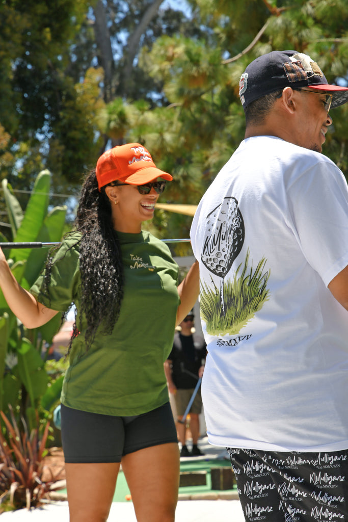 KLMulliganz golfers wearing stylish golf apparel, featuring ‘Take Your Medicine’ tee and graphic golf t-shirt, enjoying a sunny day on the course.